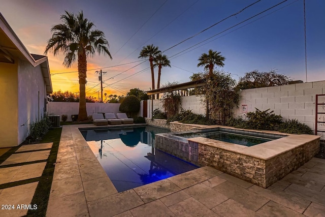 pool at dusk with an in ground hot tub