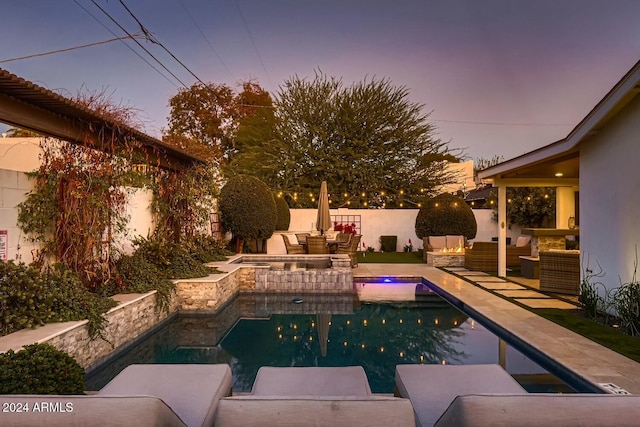 pool at dusk with an outdoor hangout area and a patio