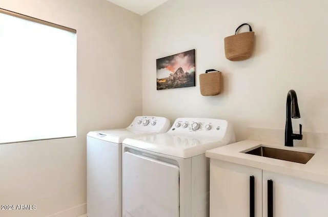 clothes washing area featuring cabinets, sink, and washer and dryer