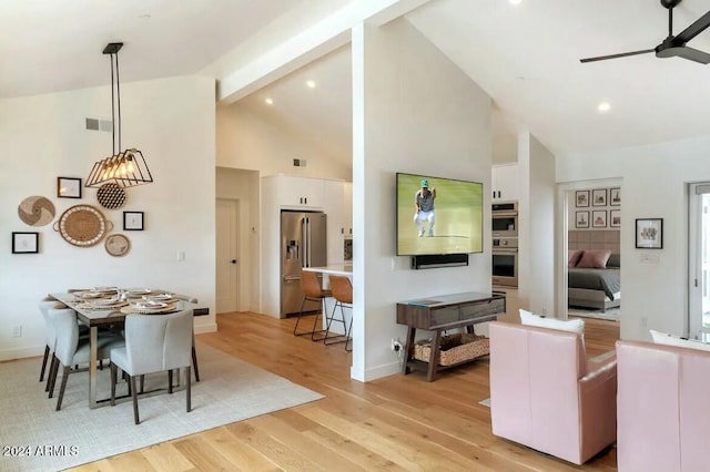 dining space with beamed ceiling, ceiling fan, light hardwood / wood-style floors, and high vaulted ceiling