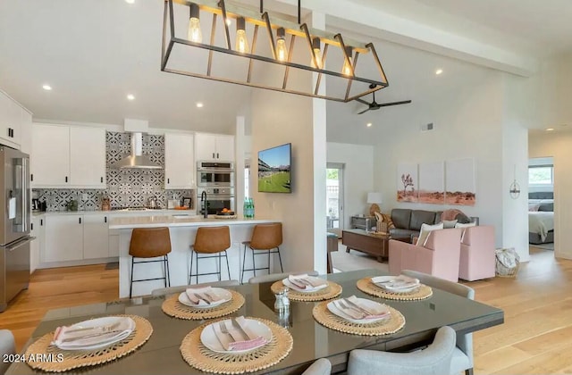 dining room featuring beamed ceiling, ceiling fan, light hardwood / wood-style floors, and a wealth of natural light