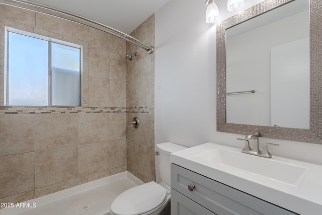 bathroom with toilet, tiled shower, and vanity