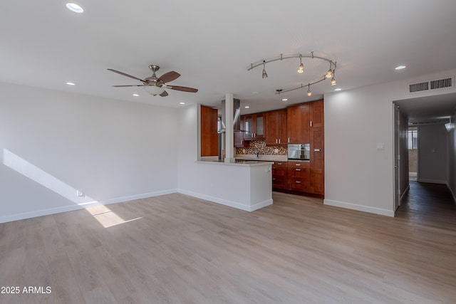 interior space featuring a ceiling fan, stainless steel oven, visible vents, ventilation hood, and backsplash
