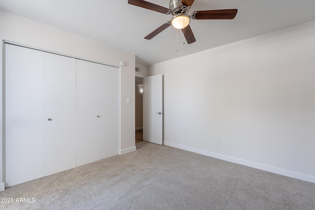 unfurnished bedroom with carpet, a closet, visible vents, baseboards, and ceiling fan