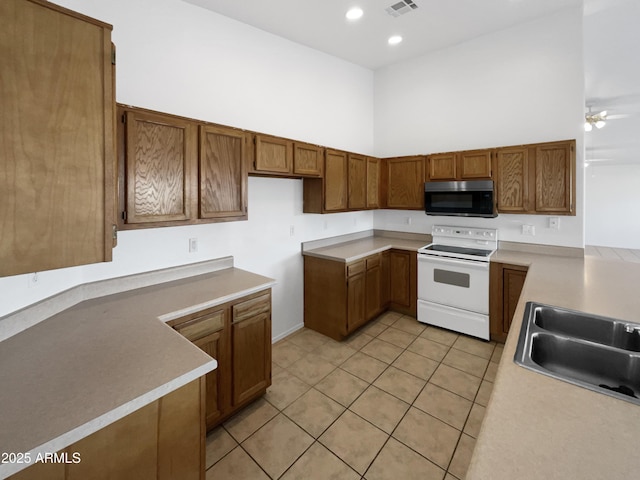 kitchen featuring a towering ceiling, sink, light tile patterned floors, ceiling fan, and white range with electric cooktop