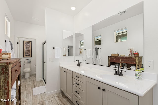 bathroom with toilet, a shower with shower door, hardwood / wood-style floors, and vanity