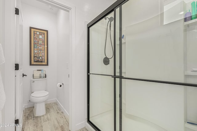 bathroom with hardwood / wood-style flooring, toilet, and an enclosed shower