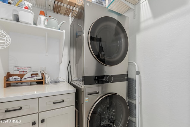 laundry area featuring stacked washer / dryer and cabinets