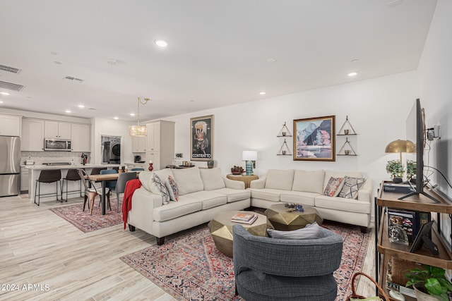 living room with light hardwood / wood-style floors and stacked washer and dryer