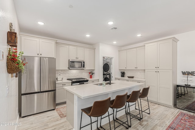 kitchen with sink, a kitchen breakfast bar, stainless steel appliances, light hardwood / wood-style flooring, and a kitchen island with sink