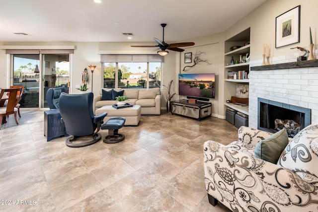 living room featuring ceiling fan, built in features, and a fireplace