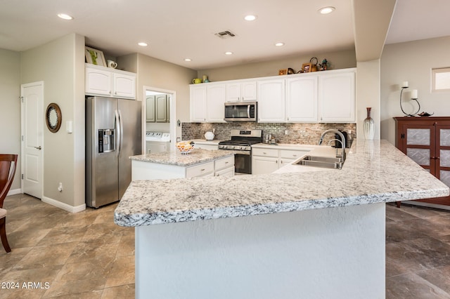 kitchen featuring kitchen peninsula, white cabinets, tasteful backsplash, sink, and stainless steel appliances