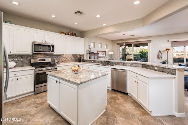 kitchen featuring appliances with stainless steel finishes, kitchen peninsula, decorative light fixtures, and sink