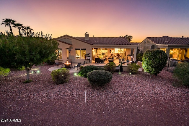 back house at dusk with a patio area and an outdoor hangout area