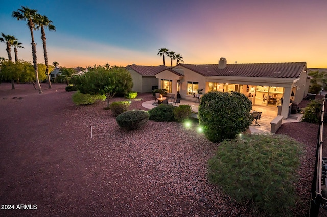 back house at dusk featuring a patio