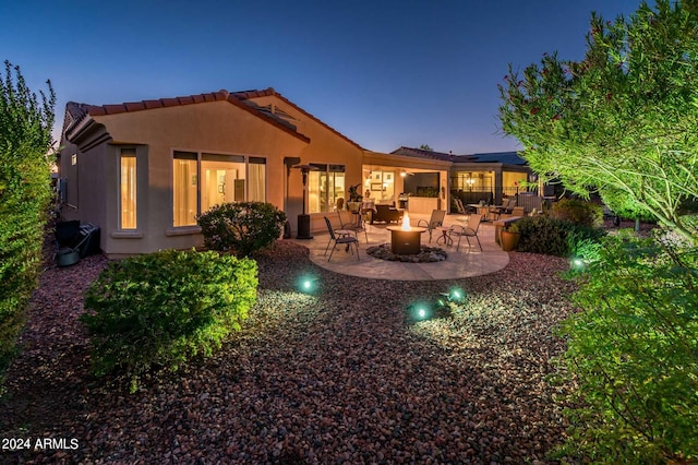 back house at dusk featuring a patio area