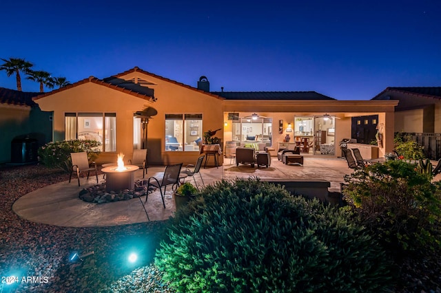 back house at night featuring a patio area