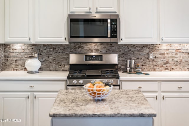 kitchen with decorative backsplash, white cabinetry, and stainless steel appliances