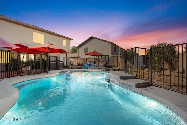 pool at dusk featuring pool water feature