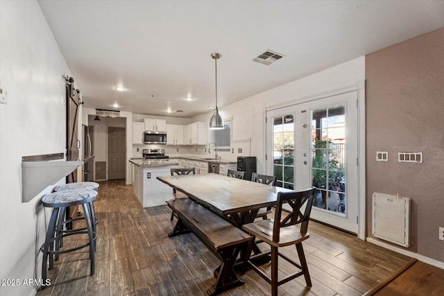 dining room with a barn door, french doors, dark hardwood / wood-style floors, and sink