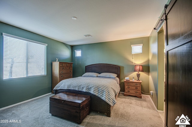 carpeted bedroom featuring multiple windows and a barn door