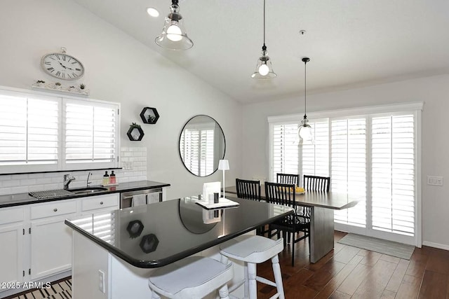 kitchen featuring lofted ceiling, dark wood-style flooring, decorative backsplash, white cabinets, and dark countertops