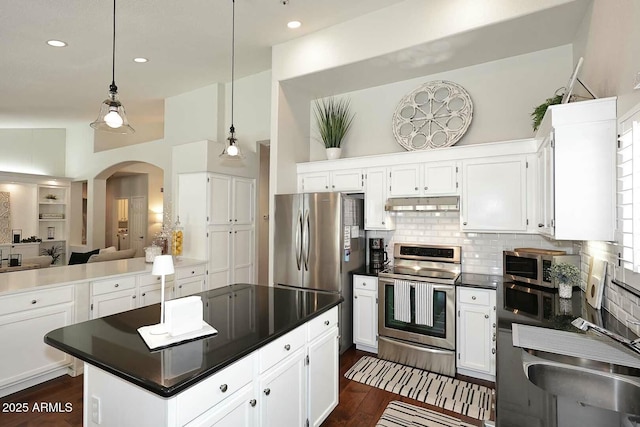 kitchen featuring under cabinet range hood, dark countertops, appliances with stainless steel finishes, and white cabinetry