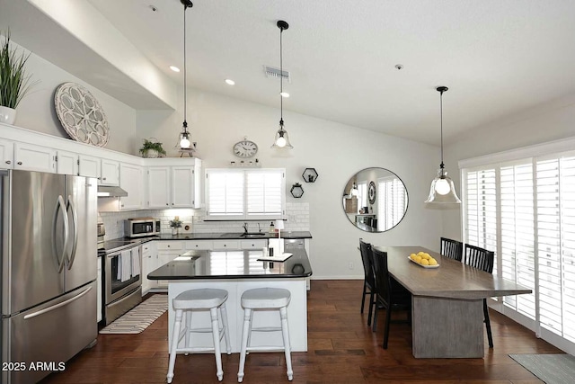 kitchen featuring dark countertops, visible vents, backsplash, under cabinet range hood, and stainless steel appliances