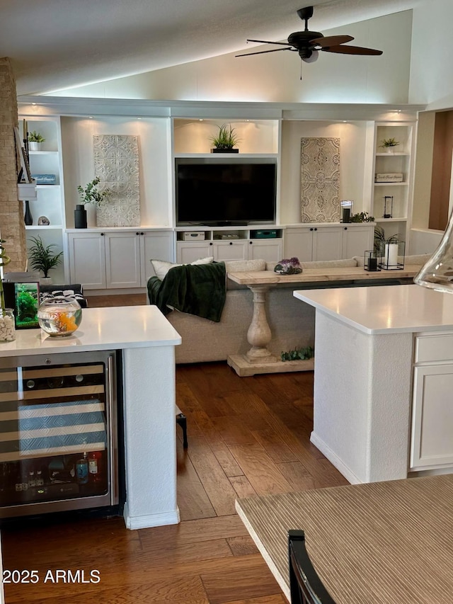 kitchen featuring dark wood-type flooring, wine cooler, light countertops, vaulted ceiling, and white cabinetry