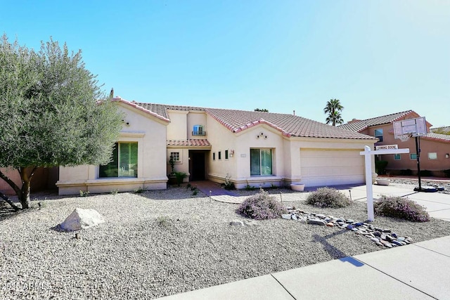 mediterranean / spanish home with stucco siding, an attached garage, a tile roof, and driveway