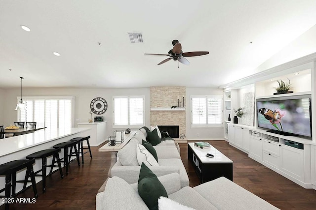 living area with visible vents, a ceiling fan, recessed lighting, a stone fireplace, and dark wood-style flooring