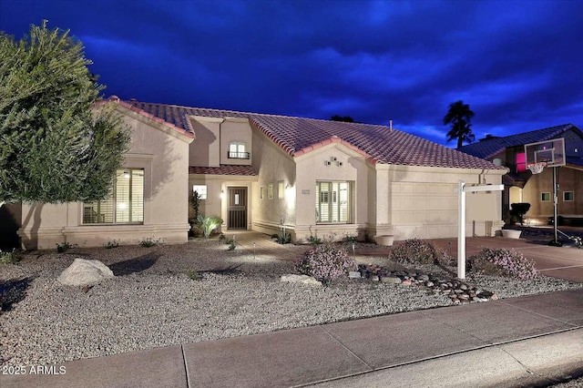 mediterranean / spanish house with concrete driveway, a tiled roof, an attached garage, and stucco siding