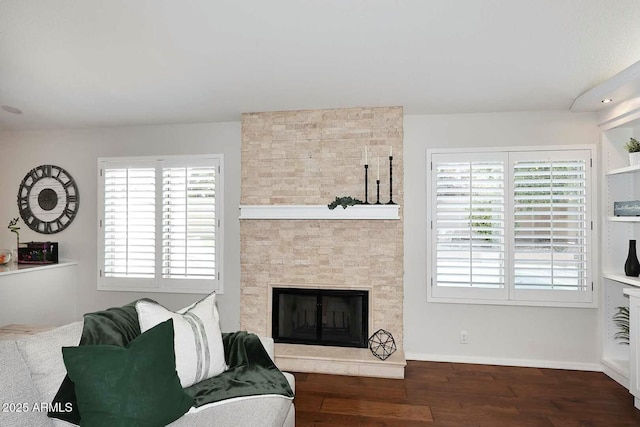 living area with wood finished floors, baseboards, and a large fireplace