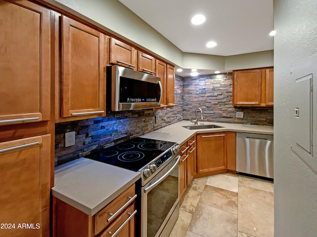 kitchen with brown cabinetry, a sink, decorative backsplash, light countertops, and appliances with stainless steel finishes