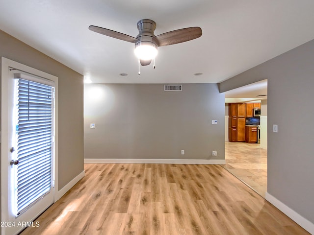 spare room with a ceiling fan, light wood-style flooring, baseboards, and visible vents