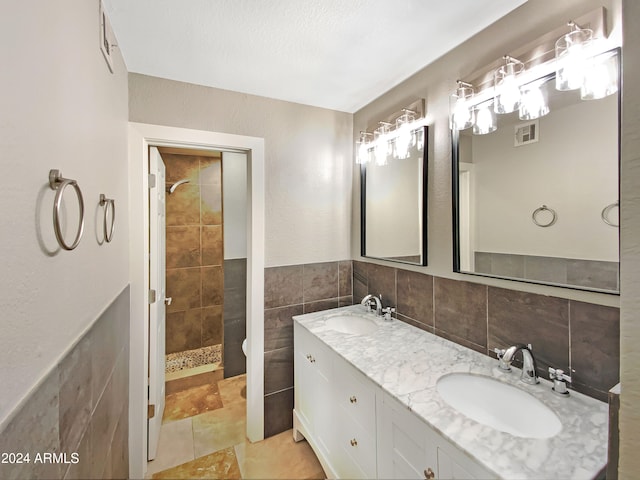 full bath featuring a sink, visible vents, tile walls, and a tile shower