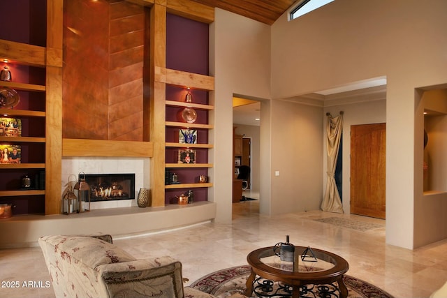 living room featuring a high ceiling, a tile fireplace, and built in shelves