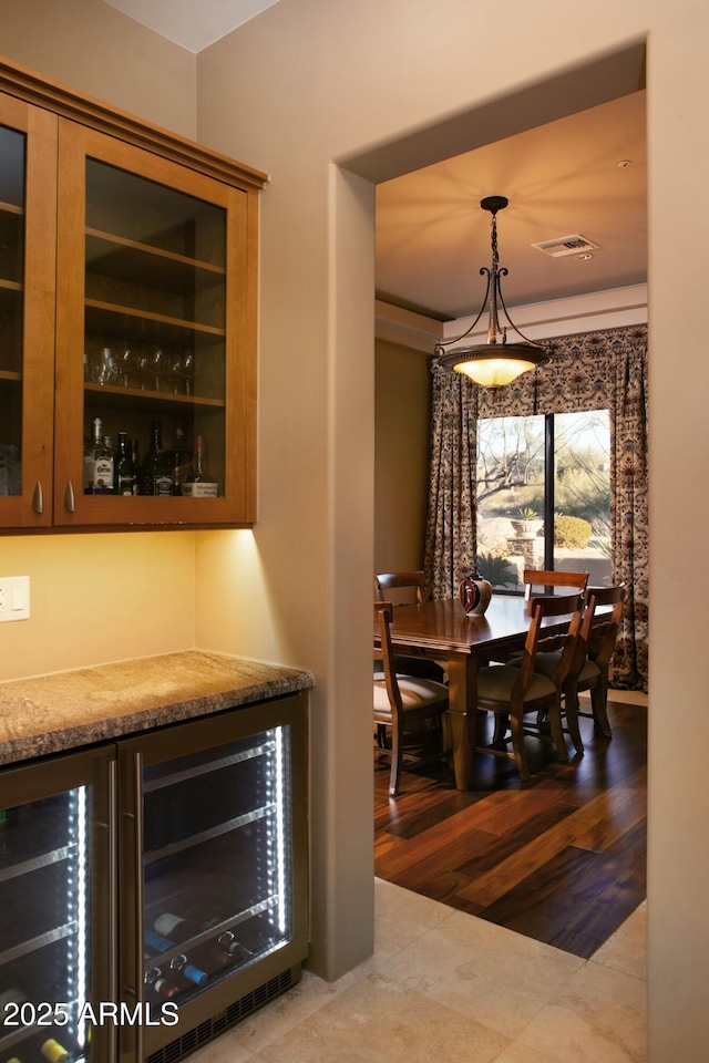 dining area featuring beverage cooler, bar area, and light wood-type flooring