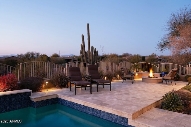 pool at dusk with a patio and an outdoor fire pit