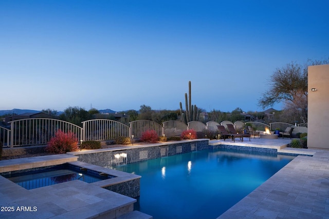 pool at dusk featuring an in ground hot tub and a patio