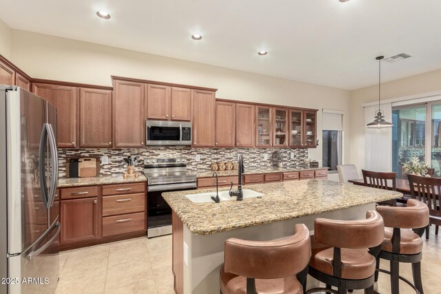 13102 S 177th Dr, Goodyear, AZ 85338 - kitchen with appliances with stainless steel finishes, decorative light fixtures, an island with sink, sink, and light stone countertops