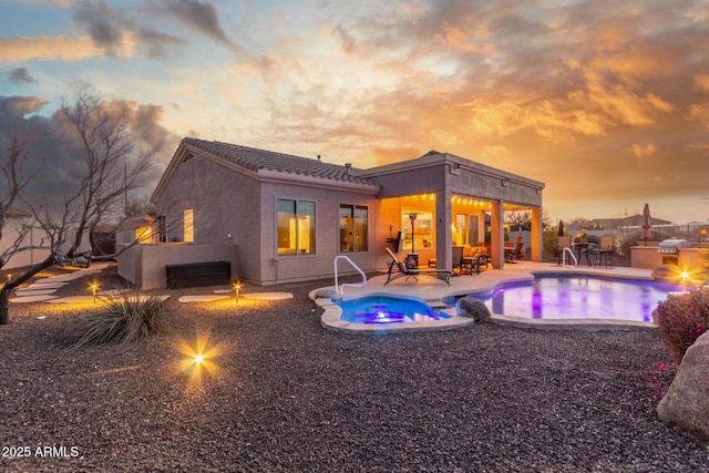 13102 S 177th Dr, Goodyear, AZ 85338 - pool at dusk featuring an in ground hot tub, an outdoor kitchen, and a patio