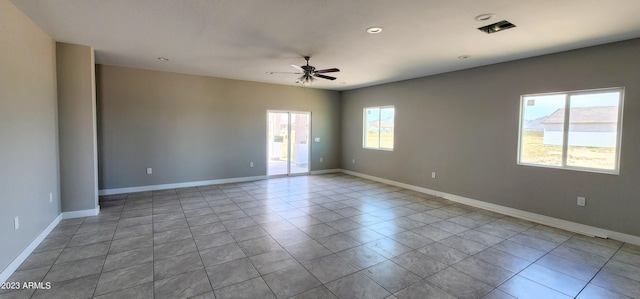 tiled empty room featuring ceiling fan and a healthy amount of sunlight