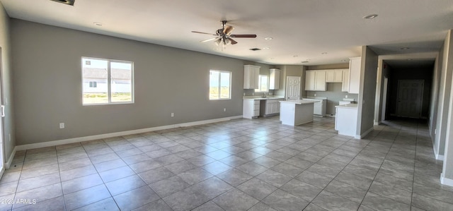 unfurnished living room with light tile flooring, ceiling fan, and sink