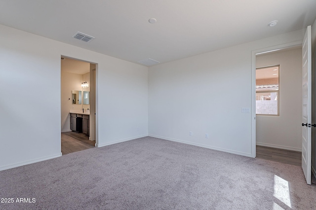 unfurnished bedroom with carpet floors, baseboards, ensuite bathroom, and visible vents