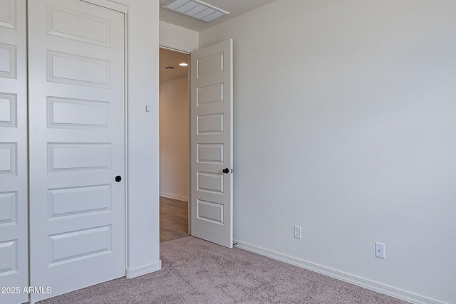 unfurnished bedroom with visible vents, baseboards, a closet, and light colored carpet