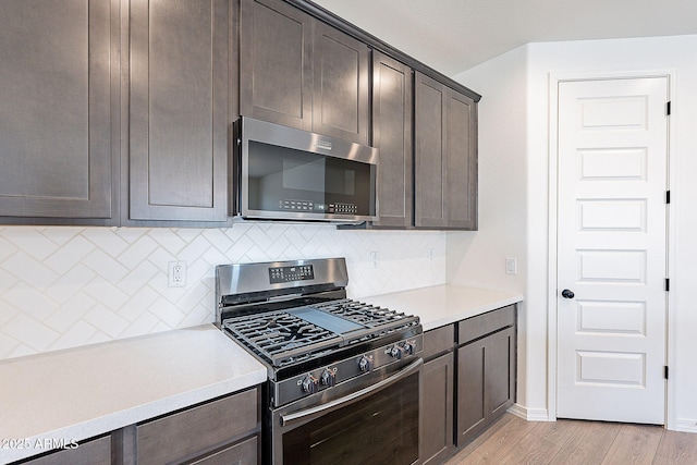 kitchen featuring light countertops, decorative backsplash, dark brown cabinets, and stainless steel appliances