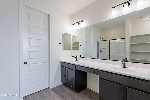 bathroom featuring a stall shower, wood finished floors, a sink, and visible vents