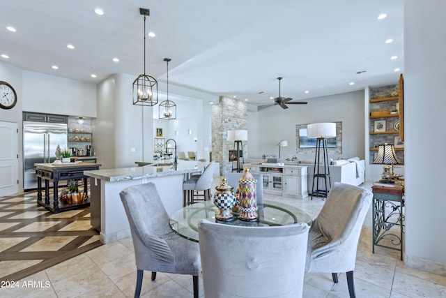 dining space with a fireplace, ceiling fan, and sink