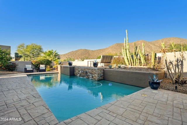 view of pool featuring pool water feature, a mountain view, a patio, and an outdoor kitchen